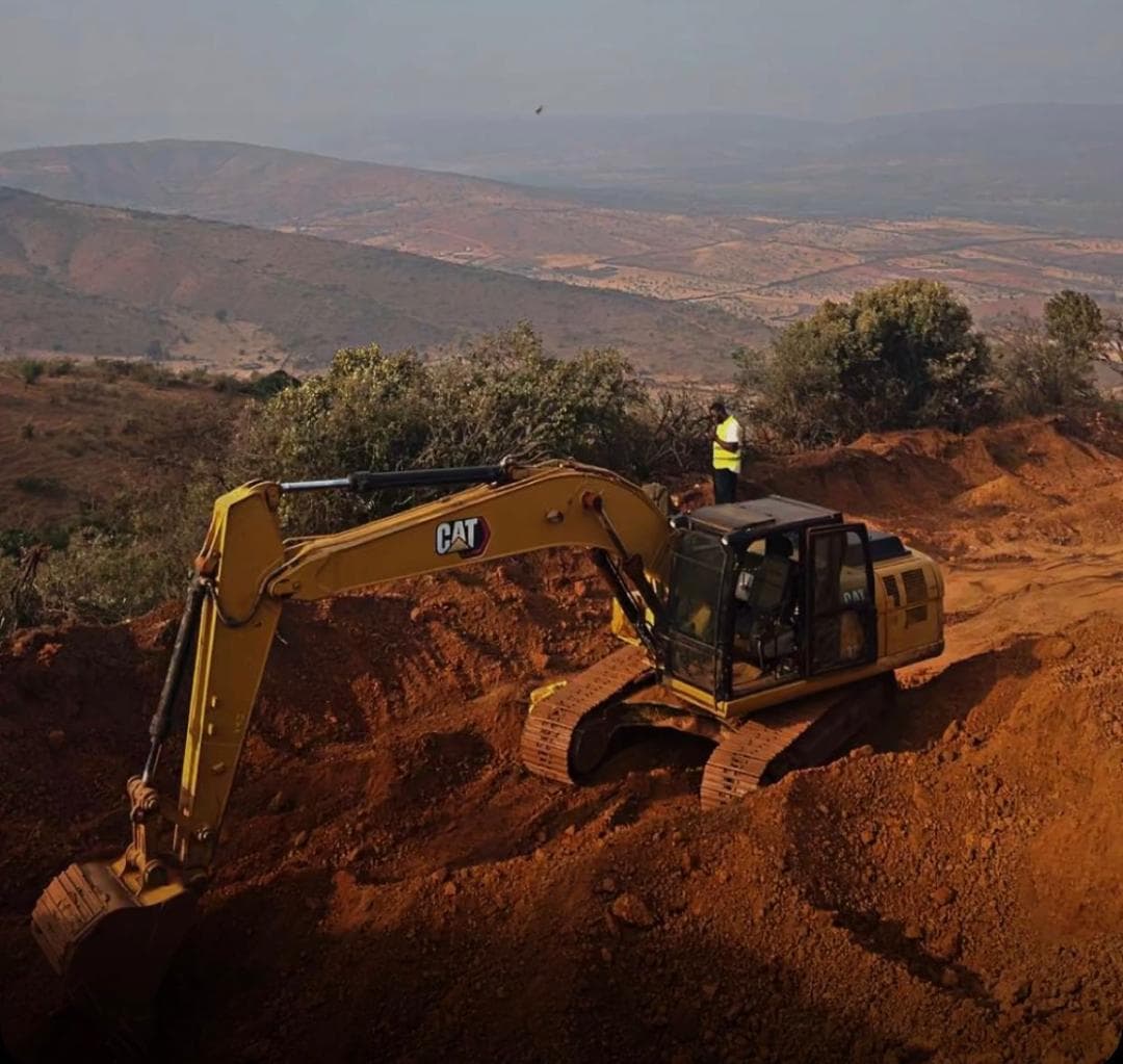 Caterpillar excavator working a hillside with the Rwandan valley behind